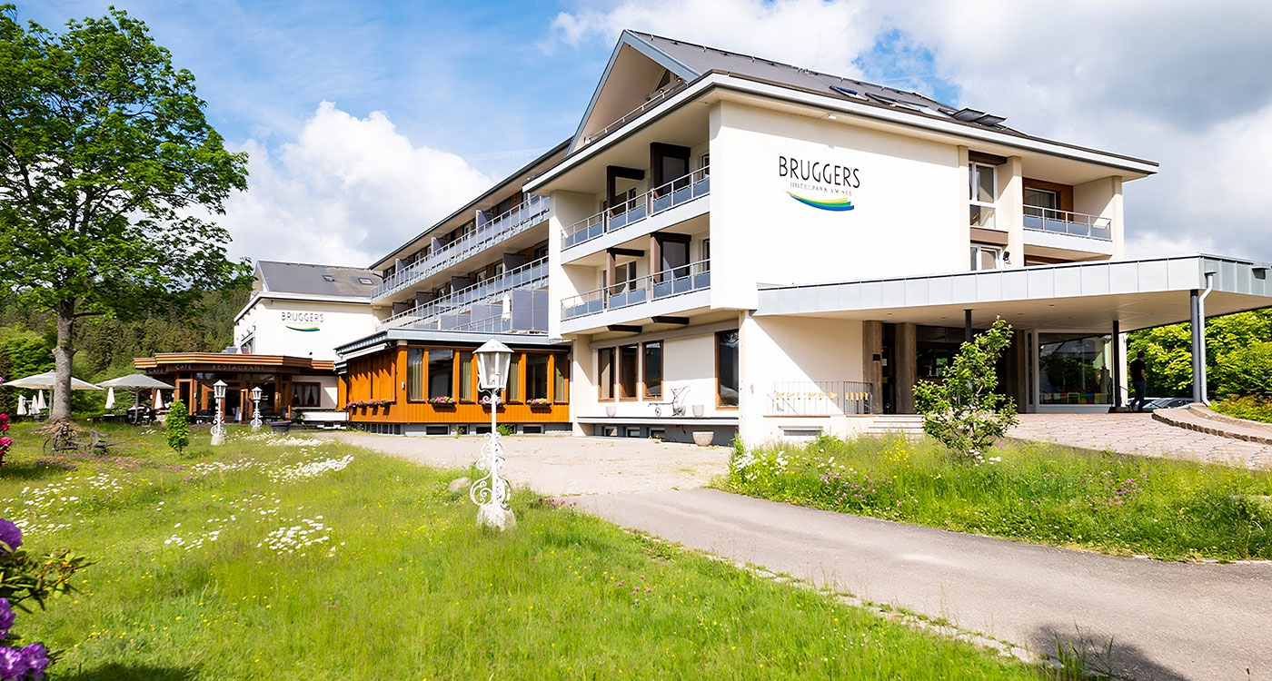 Hotel Brugger im Sommer mit grüner Umgebung und blauen Himmel 