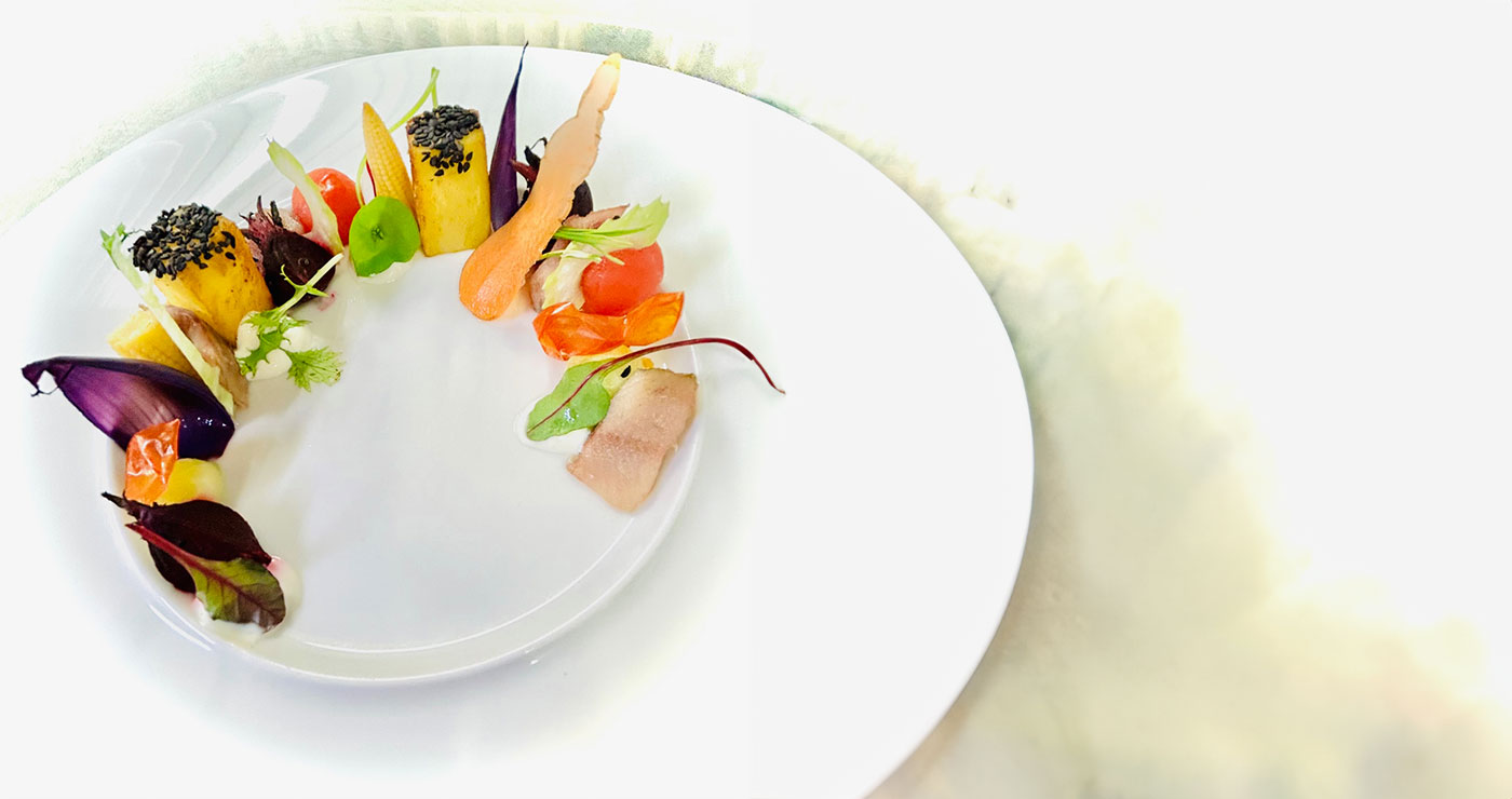 Ein kunstvoll angerichtetes Gericht mit Karotten, Tomaten und violetten Blättern