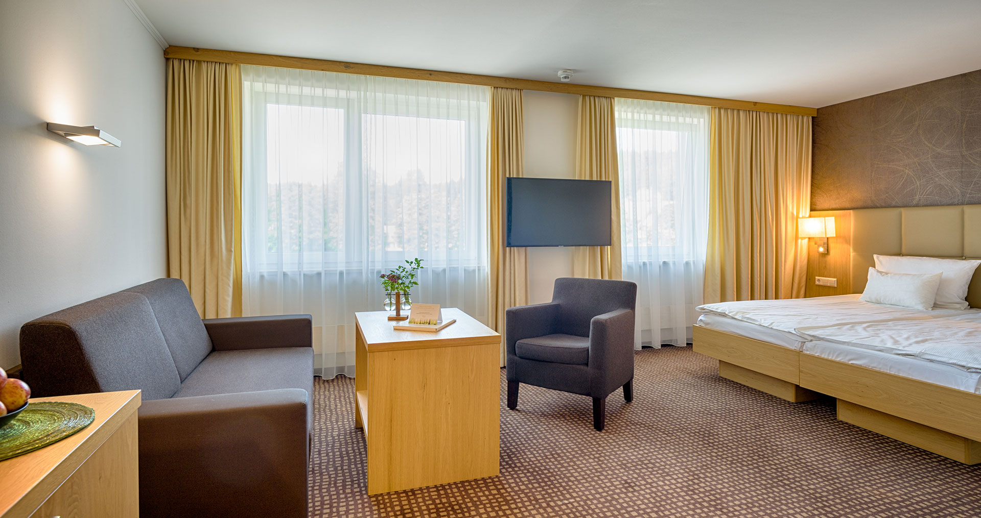 Ein Zimmer mit Sitzecke und großen Doppelbett