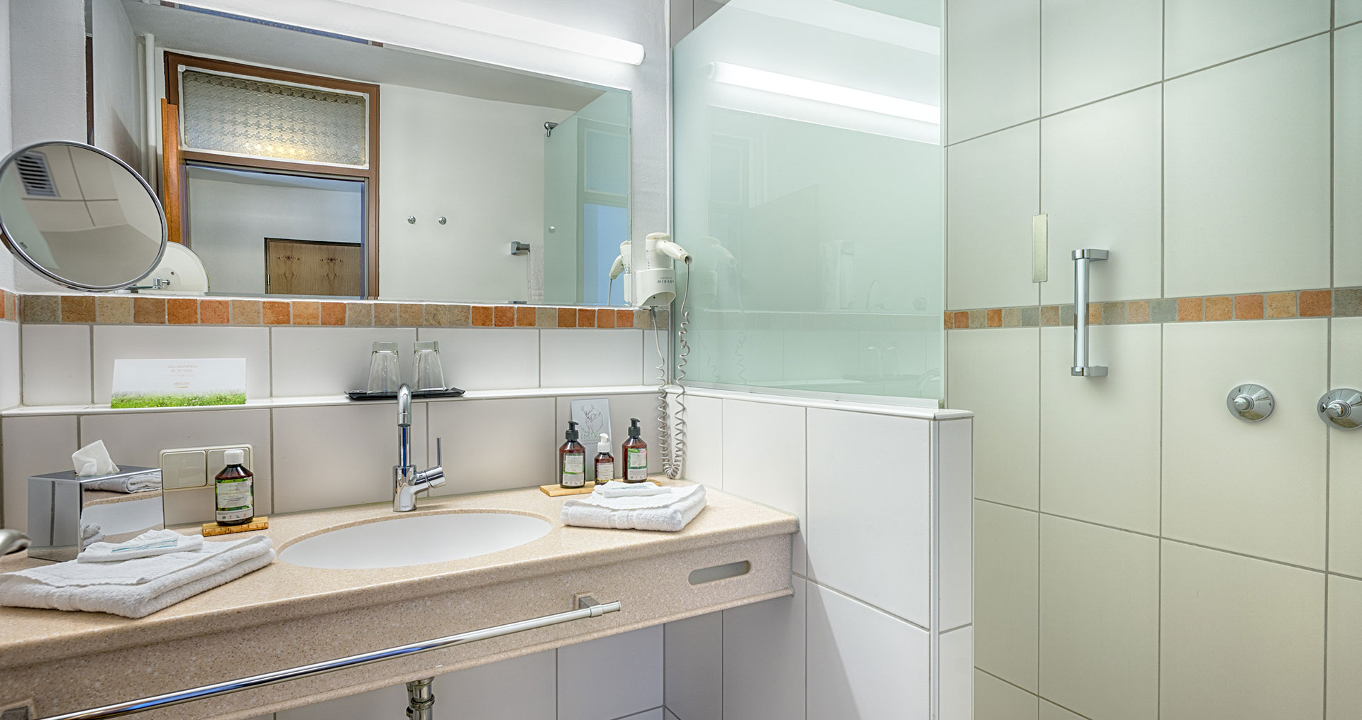 Auf der Ablage beim Waschbecken sind Pflegeprodukte zu sehen