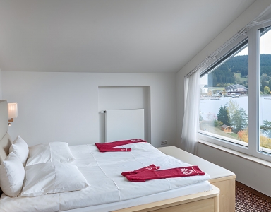 Ein Bett mit Blick auf ein Panoramafenster zum See