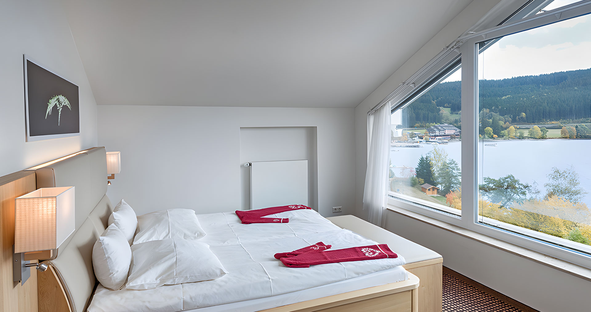 Ein Bett mit Blick auf ein Panoramafenster zum See