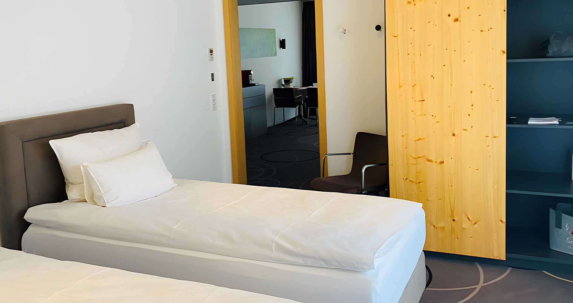 Zwei Einzelbetten und ein heller Schrank im Zimmer.