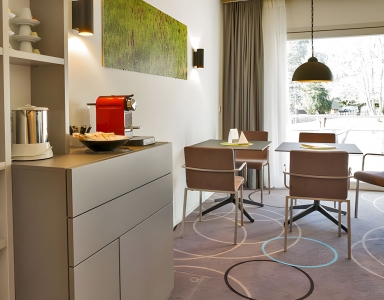 Essbereich mit Tisch, Stühlen und Kaffeemaschine.