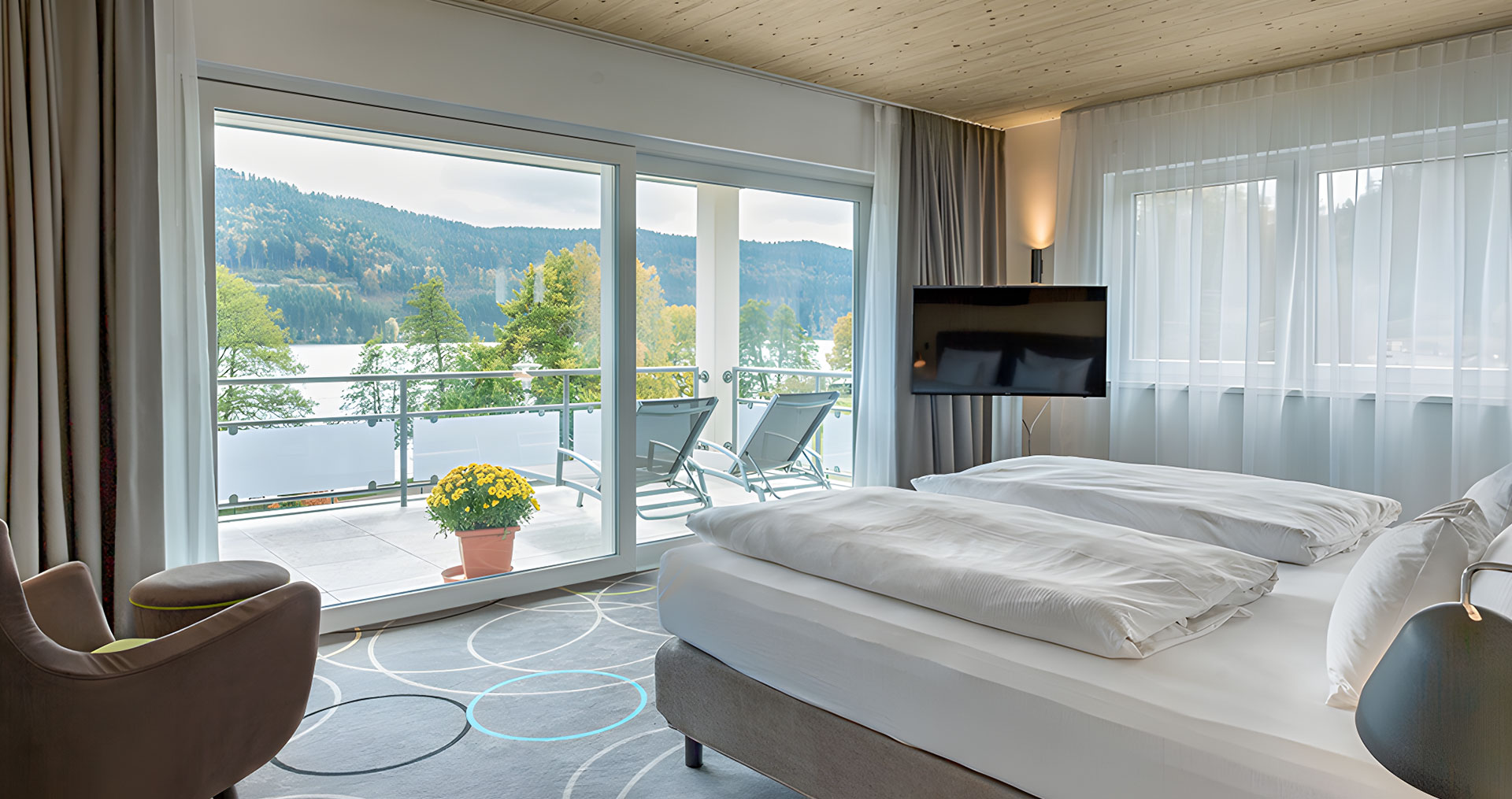 Zimmer mit Doppelbett und Panoramablick auf See.