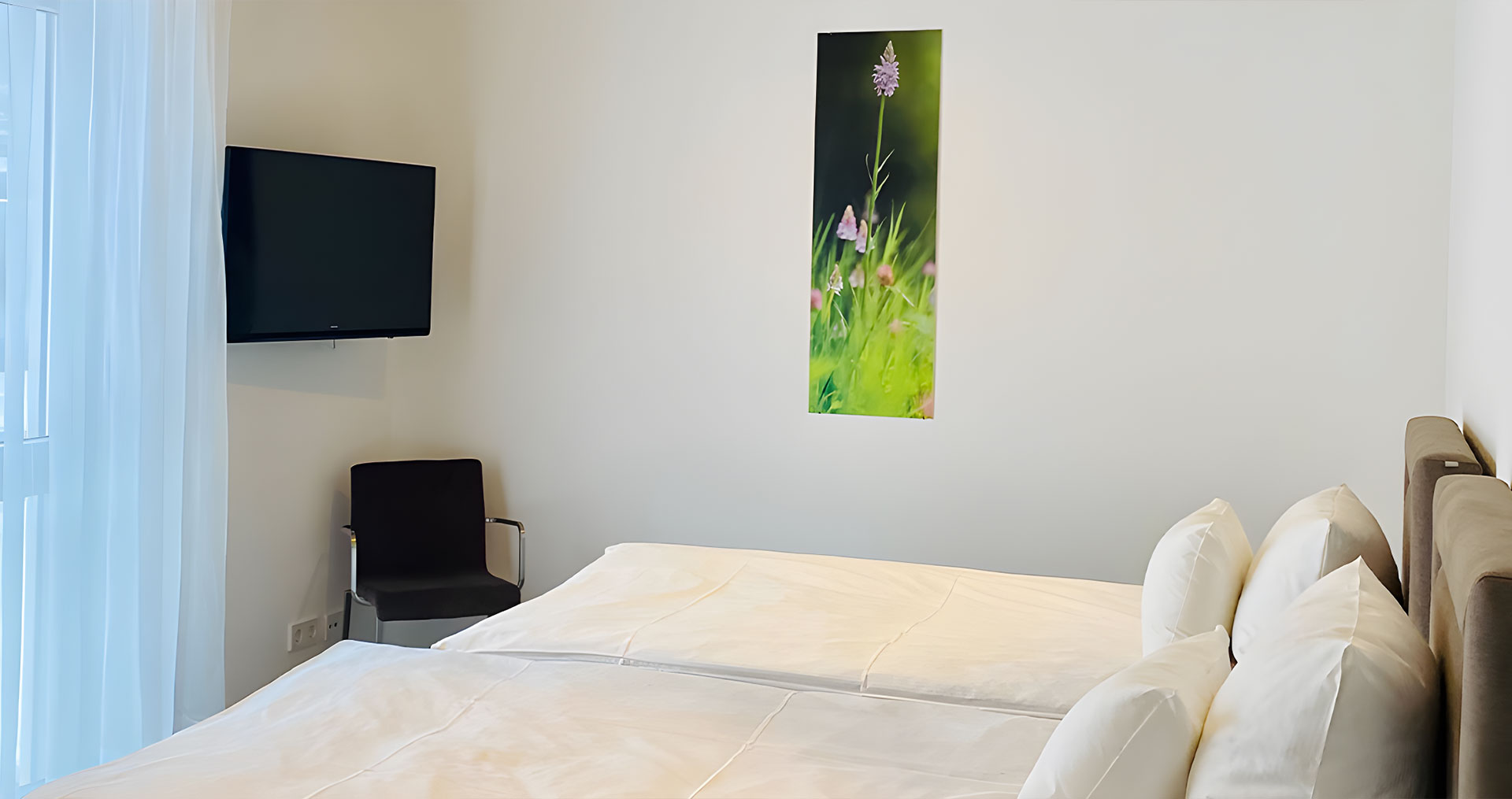 Helles Schlafzimmer mit Kunstwerk und Fernseher.